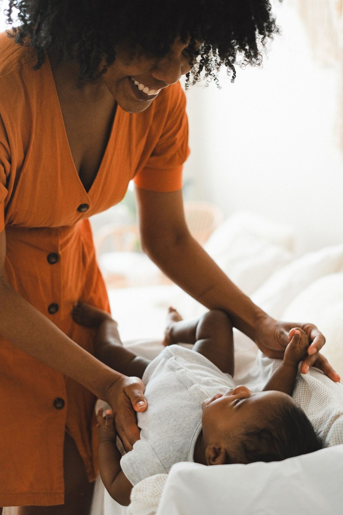 A Black mother laughing with her baby at home